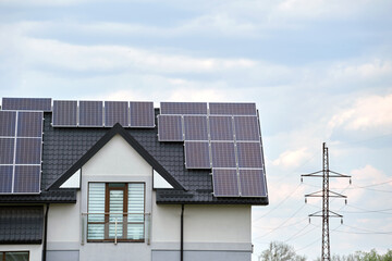 Obraz premium Private home roof covered with solar photovoltaic panels for generating of clean ecological electric energy in suburban rural town area. Concept of autonomous house