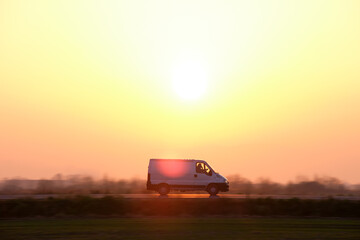Fototapeta na wymiar Small cargo van driving on highway hauling goods. Delivery transportation and logistics concept