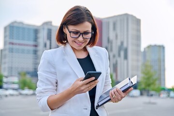 Portrait of successful mature businesswoman with smartphone outdoor