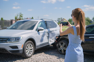 Stressed woman driver taking photo on mobile phone camera after vehicle collision on street side...