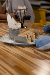 gathering of friends with a plate of taco al pastor with cilantro, served at a bar with chips and chipotle sauce