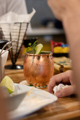 person drinking a moscow mule and eating in a bar with several friends