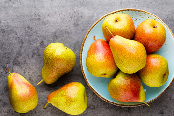 Fresh bio pear with leaves on the plate. Gray stone table.