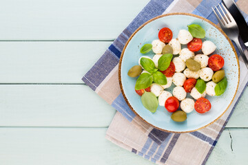 Delicious caprese salad with ripe cherry tomatoes and mini mozzarella cheese balls with fresh basil leaves.