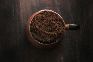Top view of clay cup with ground coffee on dark wooden background. Instant coffee for decoration in cup.