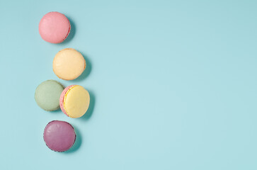 Sweet colorful macarons isolated on blue background. Tasty colorful macaroons. Top view.