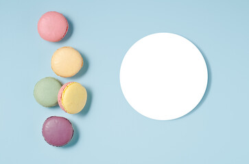 Sweet colorful macarons isolated on blue background. Tasty colorful macaroons. Top view.