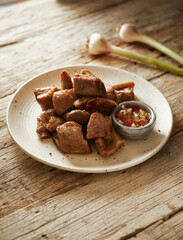 Homemade fritada a typical ecuadorian dish that consists on braised pork. It’s served on a white plate with chilli and tostado, with a traditional and wooden background 