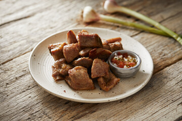 Homemade fritada a typical ecuadorian dish that consists on braised pork. It’s served on a white plate with chilli and tostado, with a traditional and wooden background 