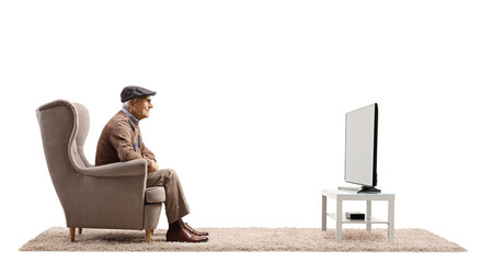 Profile shot of a pensioner sitting in an armchair and watching tv