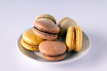 colored macaroons in a plate on a white background, close-up