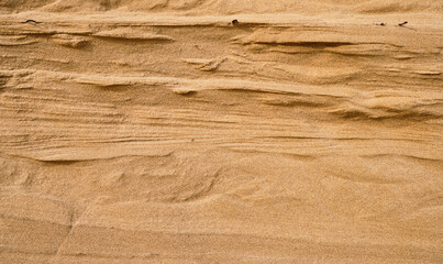 Fototapeta na wymiar Natural sandstone texture background, wall cut on a sand dune or dune, sandy background for summer designs or backgrounds.