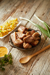 Homemade fritada a typical ecuadorian dish that consists on braised pork. It’s served on a white plate with motepillo and with a traditional and wooden background 