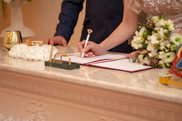 bride signs the log in the registry office. a young wife and husband. wedding. marriage...