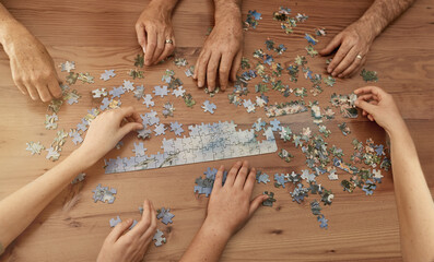 Jigsaw solutions. Shot of a group of people building a puzzle together.