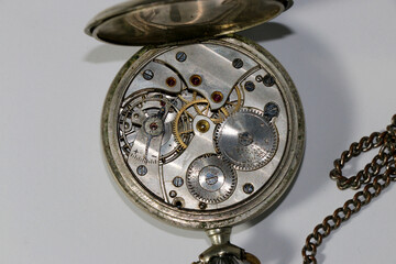 the mechanism of an old retro pocket watch on a white background