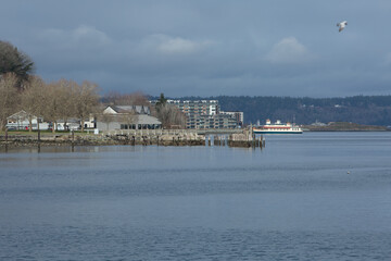 Naklejka premium Photo of a fishing pier, restaurants, buildings, and a ferry on the Puget Sound in Tacoma, Washington.