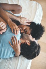 I cant help but kiss you whenever I can. High angle shot of an affectionate middle aged man kissing his wife on her forehead while lying on their bed at home.