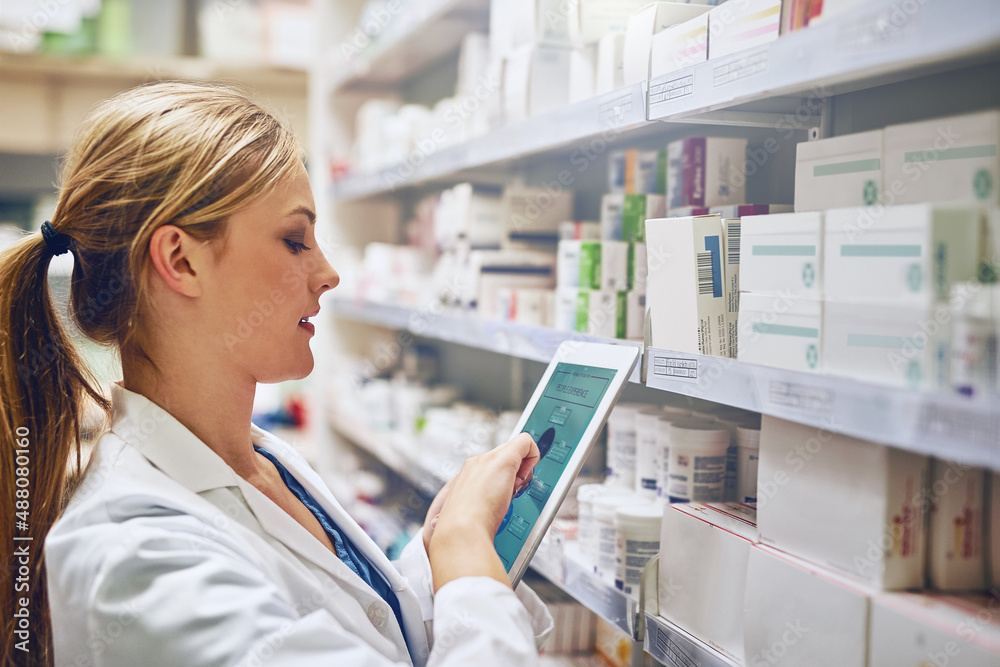 Poster doing what it takes to give you the best care. shot of a pharmacist using her digital tablet while w