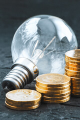 Energy saving.Old lamp. Money coins on a dark background. Energy saving. Stack of coins