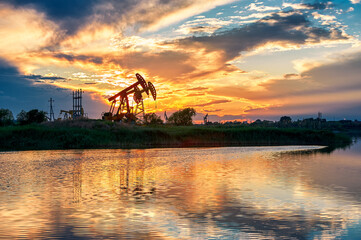 The  oil sucking machines at lakeside sunrise in Daqing oil fields, China.