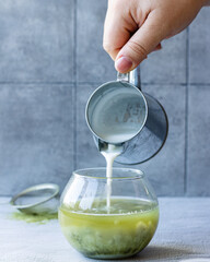 hand pouring a glass of matcha tea 