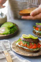 person holding a sandwich with red fish and kiwi fruit 