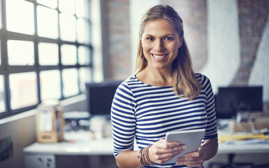 I make a living creatively. Portrait of a young designer using her digital tablet in her office.