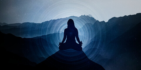 Silhouette of a woman in the lotus position and space, meditation, yoga. Mountain horizontal infinity background. Sunset. Blue hues. Mystical. Spiritual. Meditation on high mountain.