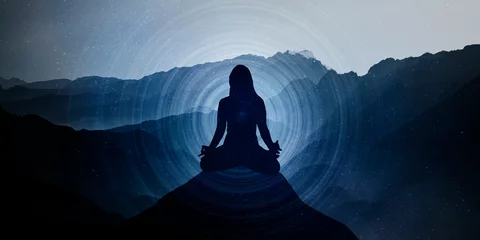 Poster Silhouette of a woman in the lotus position and space, meditation, yoga. Mountain horizontal infinity background. Sunset. Blue hues. Mystical. Spiritual. Meditation on high mountain. © vegsingh