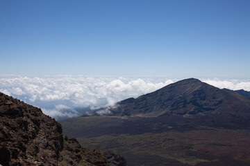 A scenic view above a blanket of white fluffy clouds seen from the top of Mt. Haleakala in Maui, Hawaii. 