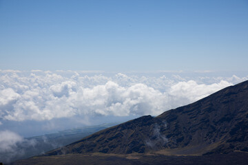 Fototapeta na wymiar A scenic view above a blanket of white fluffy clouds seen from the top of Mt. Haleakala in Maui, Hawaii. 
