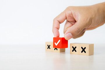 Hand choose check mark on cube wooden toy block stack with cross symbol for true or false changing mindset or way of adapting to change leader and transform quiz answer and poll concept
