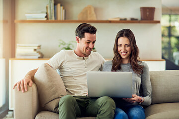 The online experience is even better when its shared. Shot of a happy young couple using a laptop together on the sofa at home.