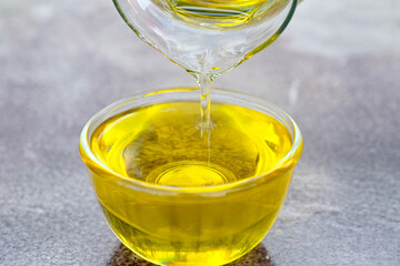 Pouring olive oil in the a glass bowl at stone kitchen and inside green garden view. Prepare for cooking concept. Healthcare and Beauty Concept.