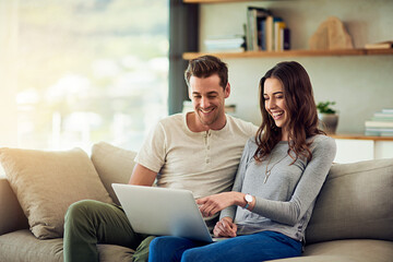Sharing an online world. Shot of a happy young couple using a laptop together on the sofa at home.