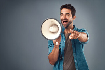 Youre our winner of the day. Studio shot of a handsome young man using a megaphone against a grey background. - obrazy, fototapety, plakaty