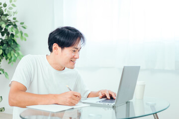 家でパソコンを使って勉強する男性（笑顔）
