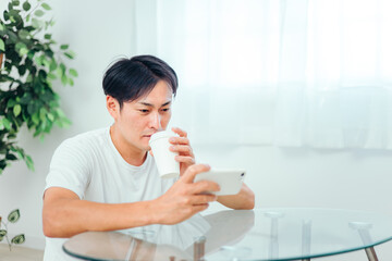 部屋でスマホを見る男性（微笑み）
