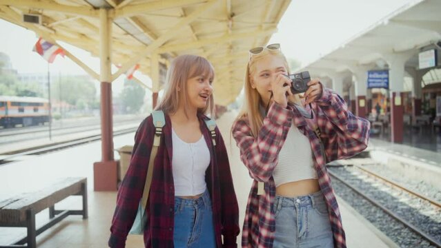 Asian girl taking photos for her close friends during going out on a trip at railway station posting pictures on online young lgbt lesbian, freedom lifestyle.