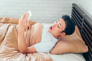 ベッドで寝ながらスマホを見る男性（ショック）

