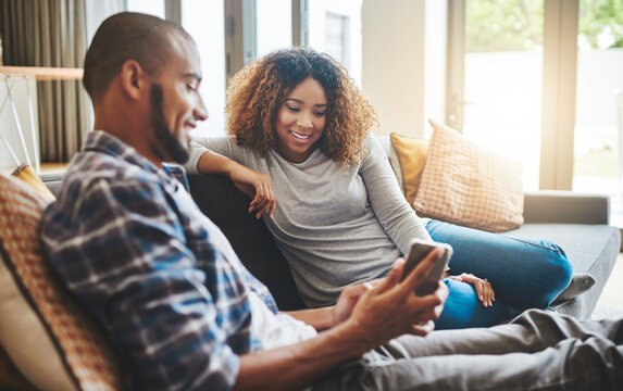 The Healthy Marriage Keeps The Lines Of Communication Open. Shot Of A Young Couple Relaxing On The Sofa At Home And Using A Mobile Phone Together.