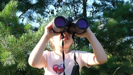 Little girl using binoculars in the forest. Exploring the world. Outdoor activities. Adventure