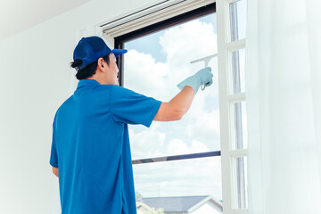窓掃除する作業着の男性
