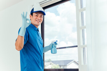 窓掃除する作業着の男性
