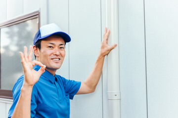 エアコンの配管化粧カバーと作業着の男性
