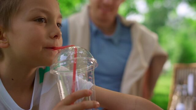 Cute boy drink juice with strow close up. Cheerful child taste fresh beverage.