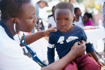 Keeping kids healthy. Shot of a volunteer doctor giving checkups to underprivileged kids.