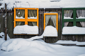snow - covered colorful window frames on a wooden fence