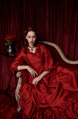  portrait of pretty female model with red hair wearing glamorous historical victorian red...